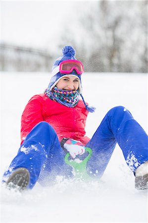 Portrait of happy young woman enjoying sled ride in snow Stock Photo - Premium Royalty-Free, Code: 693-07673111