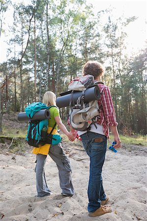 Rear view of hiking couple with backpacks walking in forest Stock Photo - Premium Royalty-Free, Code: 693-07673175