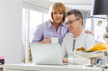 simsearch:693-07673222,k - Mature couple using laptop together at table in house Stock Photo - Premium Royalty-Free, Code: 693-07673208