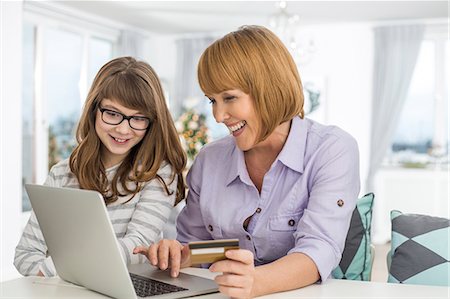 Cheerful mother and daughter shopping online at home during Christmas Photographie de stock - Premium Libres de Droits, Code: 693-07673222