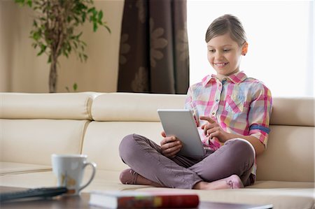 simsearch:693-07673302,k - Smiling girl using digital tablet on sofa at home Photographie de stock - Premium Libres de Droits, Code: 693-07673246