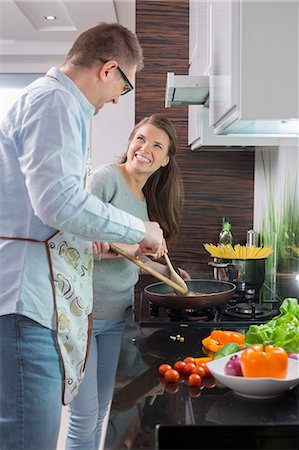 simsearch:862-05997022,k - Happy couple preparing food in kitchen Photographie de stock - Premium Libres de Droits, Code: 693-07673261