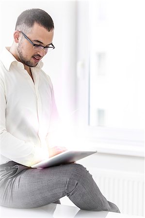 data transfer - Young businessman using digital tablet in office Stock Photo - Premium Royalty-Free, Code: 693-07673299