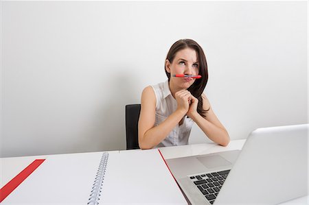 simsearch:693-07672547,k - Thoughtful businesswoman holding pen under nose at desk in office Foto de stock - Royalty Free Premium, Número: 693-07912114