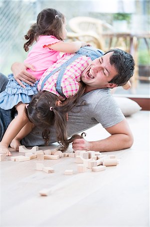 Playful daughters on top of father at home Stock Photo - Premium Royalty-Free, Code: 693-07912136