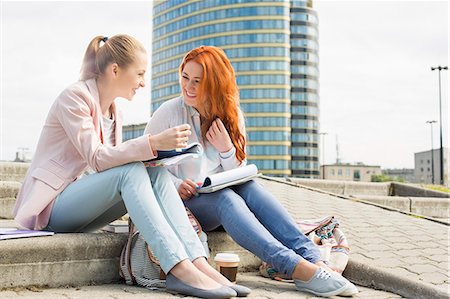 simsearch:693-07912235,k - Full length of smiling female college students studying on steps against building Foto de stock - Sin royalties Premium, Código: 693-07912248