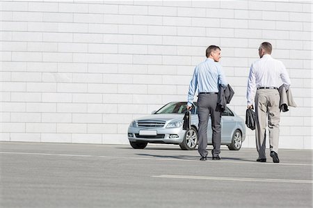 Rear view of businessmen carrying briefcases while walking towards car on street Photographie de stock - Premium Libres de Droits, Code: 693-07912258
