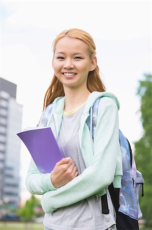 simsearch:693-07912235,k - Portrait of happy young woman holding book at college campus Foto de stock - Sin royalties Premium, Código: 693-07912252