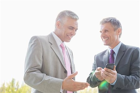 simsearch:693-07913273,k - Happy businessmen discussing over mobile phone outdoors Stockbilder - Premium RF Lizenzfrei, Bildnummer: 693-07912271