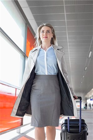 skirt walking - Young businesswoman with luggage walking in railroad station Stock Photo - Premium Royalty-Free, Code: 693-07912282