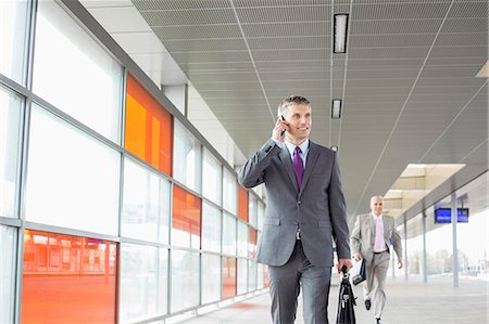 simsearch:693-07912282,k - Middle aged businessman on call while walking in railroad station Stock Photo - Premium Royalty-Free, Code: 693-07912296