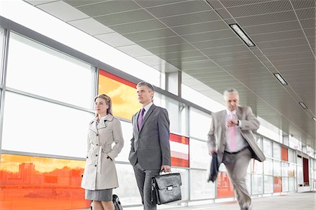 simsearch:693-06379884,k - Businesspeople walking while male colleague running in railroad station Stock Photo - Premium Royalty-Free, Code: 693-07912299