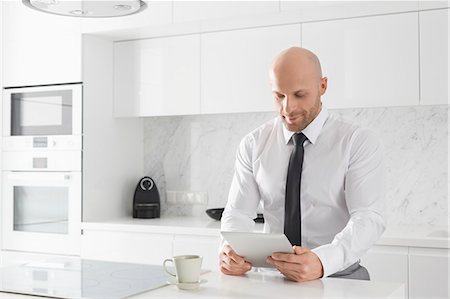 Mid adult businessman using tablet PC in kitchen Photographie de stock - Premium Libres de Droits, Code: 693-07912342