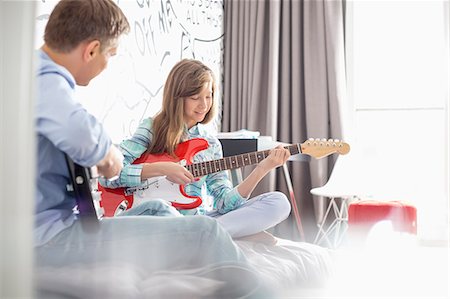 playing music - Father and daughter playing electric guitars at home Stock Photo - Premium Royalty-Free, Code: 693-07912382