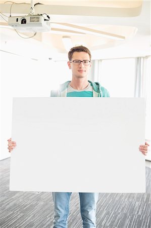 Portrait of confident businessman holding blank board in creative office Photographie de stock - Premium Libres de Droits, Code: 693-07912496