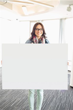 eye contact job woman presentation - Portrait of happy businesswoman holding blank sign in creative office Stock Photo - Premium Royalty-Free, Code: 693-07912497