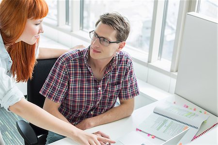 simsearch:693-03474486,k - Business couple looking at each other while using laptop in creative office Foto de stock - Sin royalties Premium, Código: 693-07912515