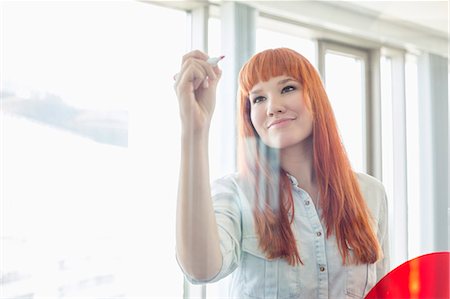 Creative businesswoman writing on glass wall in office Stock Photo - Premium Royalty-Free, Code: 693-07912523