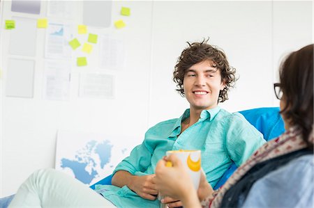 simsearch:693-07456264,k - Businesspeople having coffee while relaxing on beanbag chairs in creative office Stock Photo - Premium Royalty-Free, Code: 693-07912547