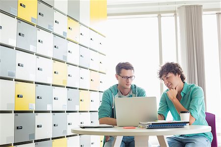 simsearch:693-07672547,k - Businessmen using laptop at table in locker room at creative office Foto de stock - Royalty Free Premium, Número: 693-07912559