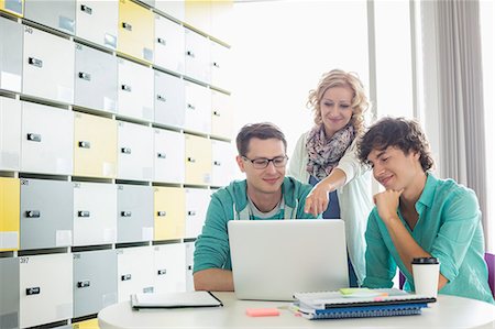 simsearch:693-07913227,k - Businesspeople using laptop at table in locker room at creative office Foto de stock - Royalty Free Premium, Número: 693-07912560