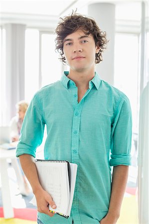 simsearch:693-07912462,k - Portrait of confident businessman holding files at creative office Stock Photo - Premium Royalty-Free, Code: 693-07912563