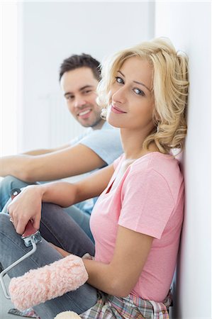 Portrait of beautiful woman holding paint roller with man in background Foto de stock - Sin royalties Premium, Código: 693-07912575