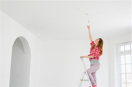 dueña - Full-length of woman on ladder fitting light bulb in new house Foto de stock - Sin royalties Premium, Código: 693-07912619