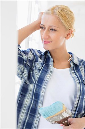 Thoughtful woman holding paintbrush at home Stock Photo - Premium Royalty-Free, Code: 693-07912633