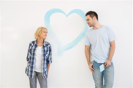 Mid-adult couple looking at each other with painted heart on wall Photographie de stock - Premium Libres de Droits, Code: 693-07912647