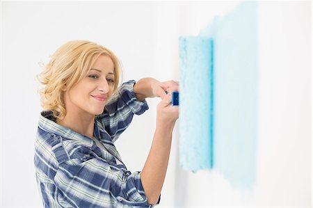 renovate house - Beautiful woman painting wall with paint roller Stock Photo - Premium Royalty-Free, Code: 693-07912655