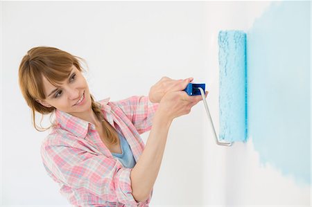 paintings in home - Beautiful woman painting wall with paint roller Stock Photo - Premium Royalty-Free, Code: 693-07912652