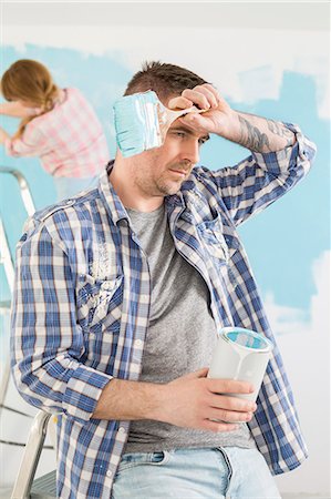 simsearch:693-07912586,k - Tired man holding paint can and brush with woman painting in background Stock Photo - Premium Royalty-Free, Code: 693-07912664