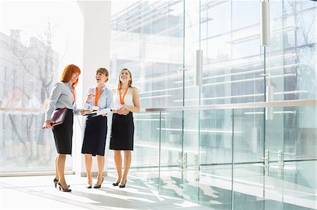 simsearch:693-07912729,k - Happy businesswomen standing against glass wall in office Stock Photo - Premium Royalty-Free, Code: 693-07912688