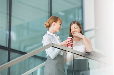 simsearch:693-07672655,k - Businesswomen gossiping while having coffee on steps in office Stock Photo - Premium Royalty-Free, Code: 693-07912695