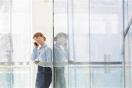 Businesswoman using cell phone in office Stock Photo - Premium Royalty-Free, Code: 693-07912690