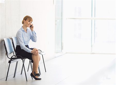 simsearch:693-08769320,k - Businesswoman using cell phone while sitting on chair in office Stock Photo - Premium Royalty-Free, Code: 693-07912691