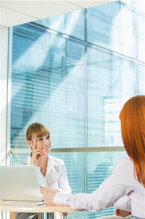 professional woman sitting focused - Businesswomen discussing at table in office Stock Photo - Premium Royalty-Free, Code: 693-07912735