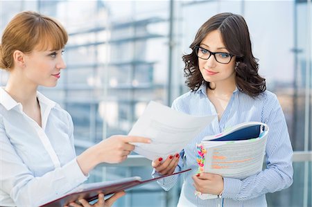 file - Businesswoman showing document to female colleague in office Stock Photo - Premium Royalty-Free, Code: 693-07912744