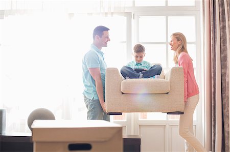 simsearch:6115-07282791,k - Happy parents carrying son on armchair in new house Stock Photo - Premium Royalty-Free, Code: 693-07912758