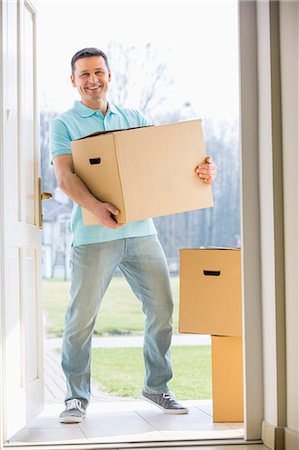 doorway - Portrait of happy man carrying cardboard box while entering new home Photographie de stock - Premium Libres de Droits, Code: 693-07912752