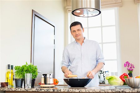 simsearch:693-07912779,k - Portrait of confident man preparing food in kitchen Foto de stock - Sin royalties Premium, Código: 693-07912779