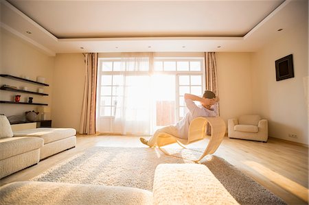 Rear view of man relaxing on modern chair at home Foto de stock - Sin royalties Premium, Código: 693-07912825