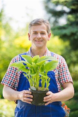 simsearch:6102-03905363,k - Portrait of happy gardener holding potted plant at nursery Stock Photo - Premium Royalty-Free, Code: 693-07912843