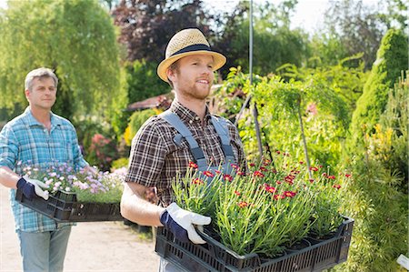 simsearch:649-03768999,k - Male gardeners walking while carrying flower pots in crates at plant nursery Stock Photo - Premium Royalty-Free, Code: 693-07912869