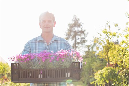 simsearch:693-07912856,k - Portrait of confident man carrying crate with flower pots in garden Stock Photo - Premium Royalty-Free, Code: 693-07912877