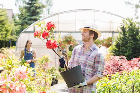 simsearch:693-07912856,k - Male gardener examining flower pot with colleague standing in background outside greenhouse Stock Photo - Premium Royalty-Free, Code: 693-07912902