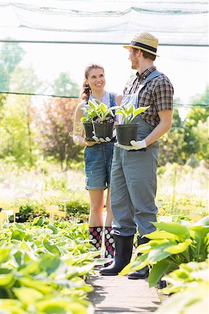 simsearch:693-07912856,k - Gardeners discussing while holding potted plants at garden Stock Photo - Premium Royalty-Free, Code: 693-07912915