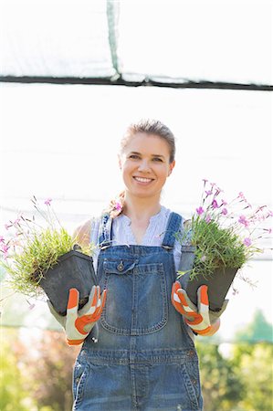 simsearch:693-07912856,k - Portrait of happy female gardener holding potted plants at greenhouse Stock Photo - Premium Royalty-Free, Code: 693-07912918