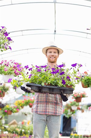 simsearch:693-07912855,k - Portrait of happy gardener holding flower pots in crate at greenhouse Stock Photo - Premium Royalty-Free, Code: 693-07912910